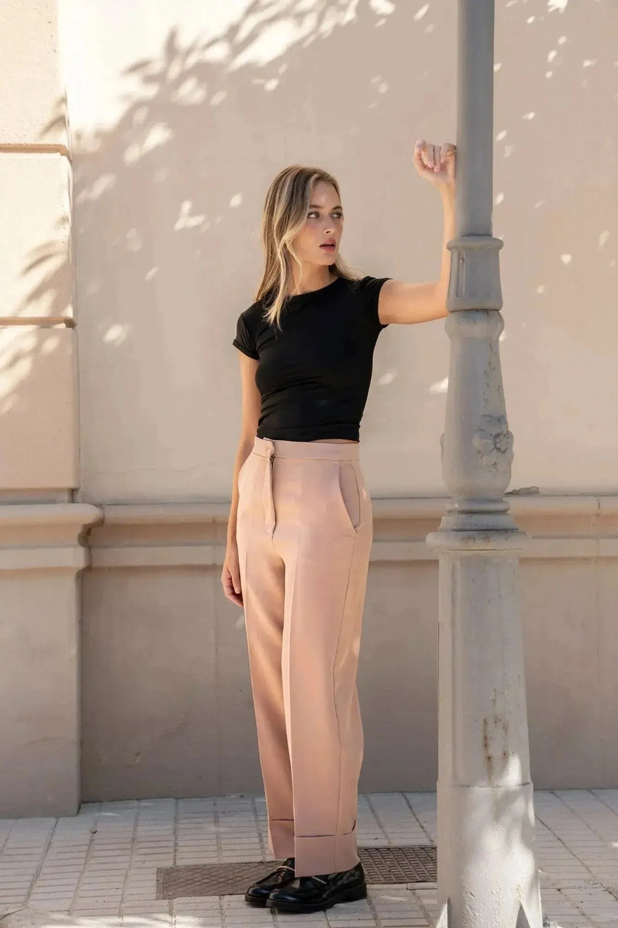 Femme dans un pantalon femme pince à revers, regardant vers la droite, près d'un lampadaire.