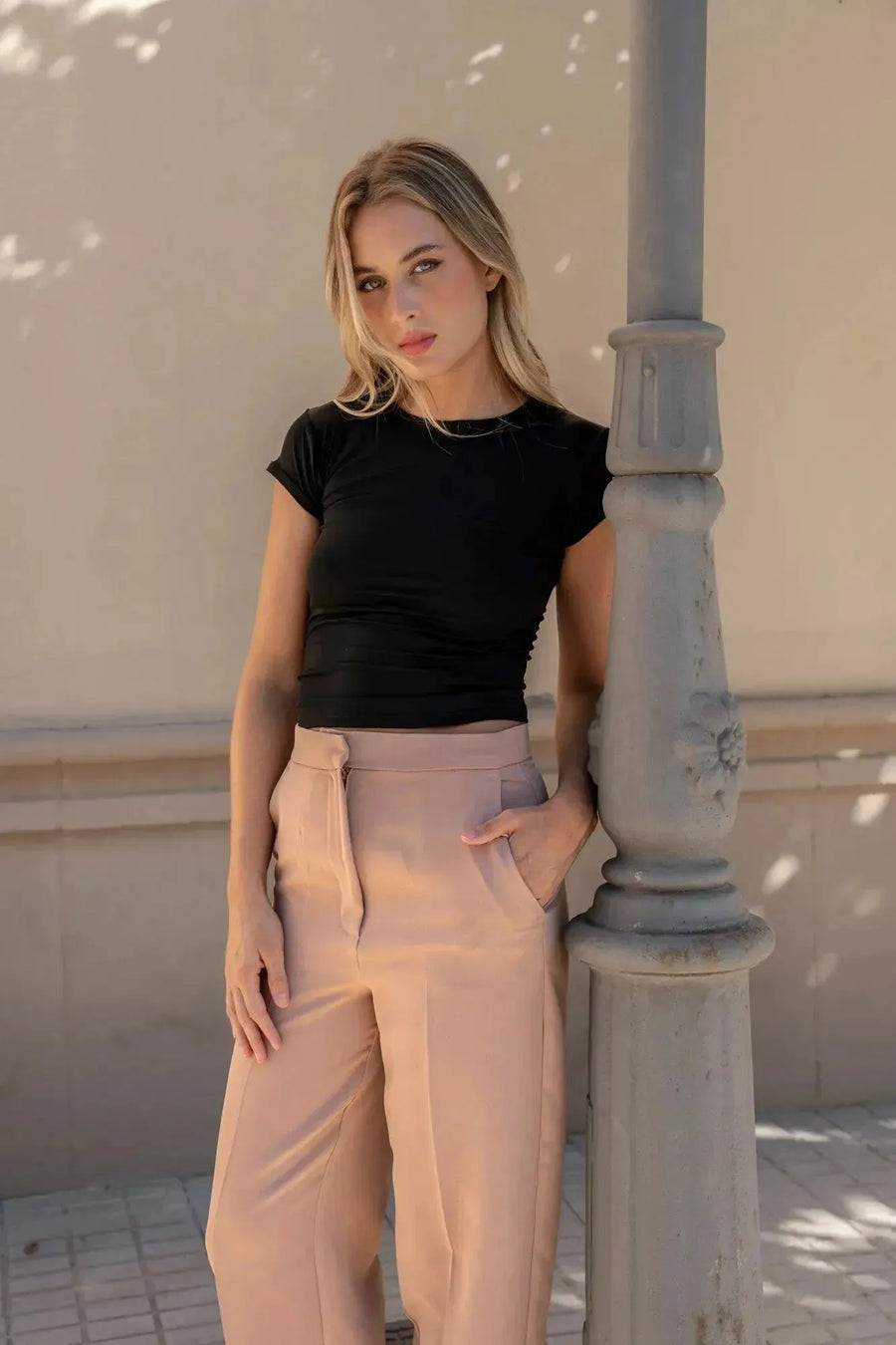 Femme portant un pantalon femme pince à revers, posant avec élégance autour d'un lampadaire.