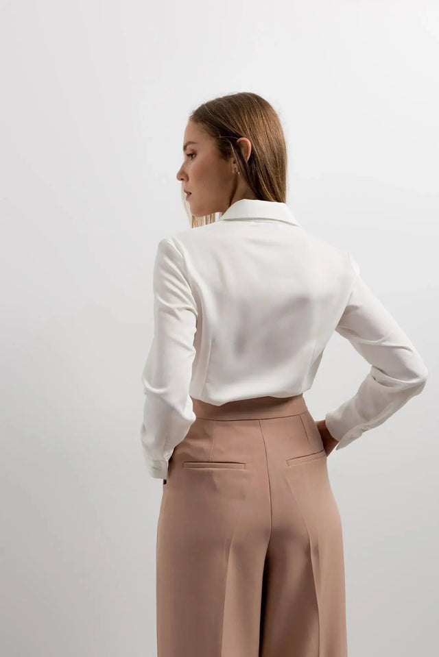 Vue arrière d'une femme portant un pantalon femme pince à revers et une chemise blanche, affichant un style classique.