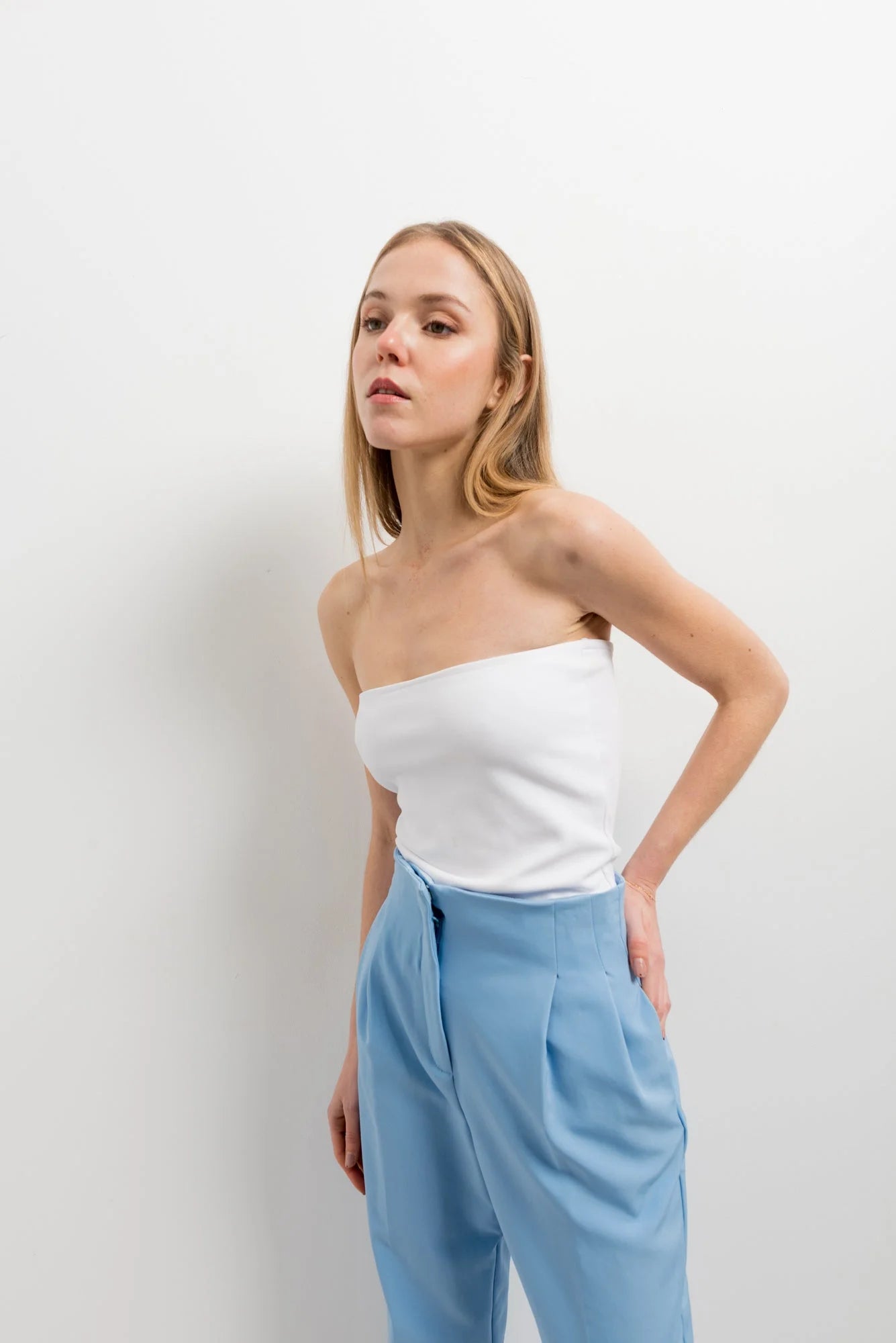 Femme portant un pantalon taille haute bleu clair et top blanc pour un style élégant