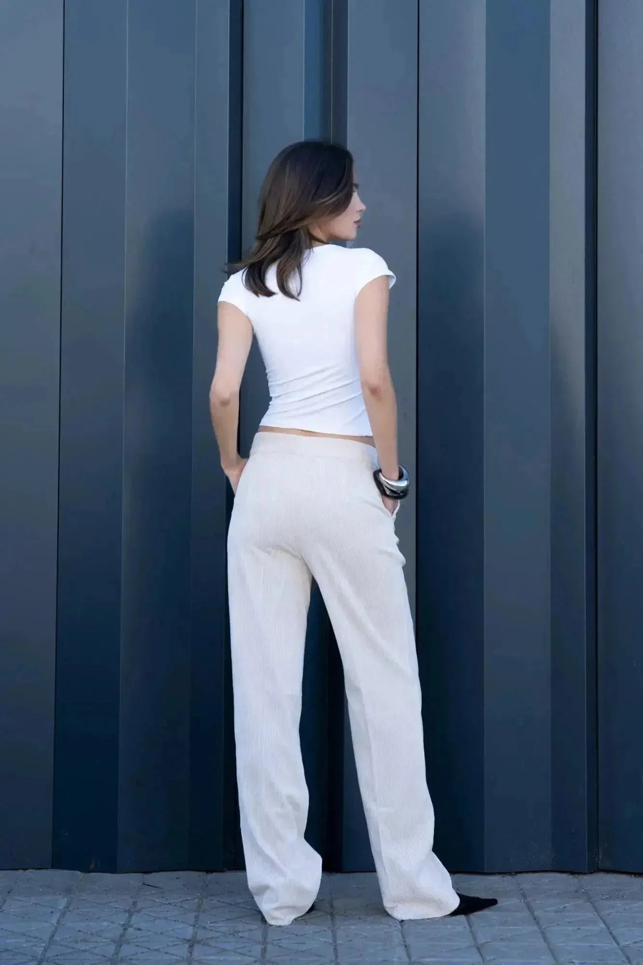 Femme portant un pantalon large en velours côtelé beige et un haut blanc