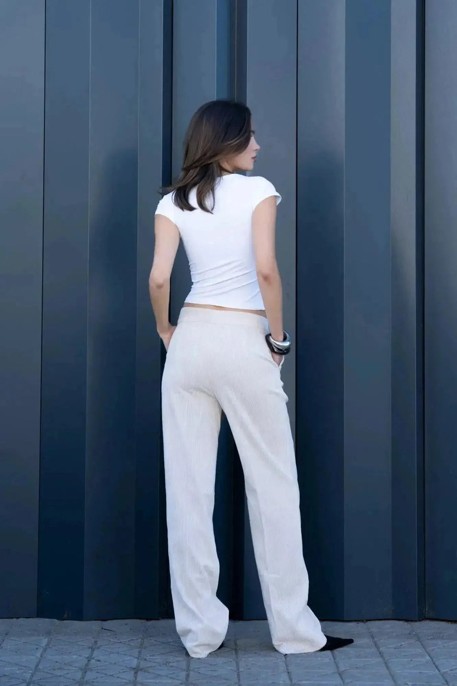Femme portant un pantalon large en velours côtelé beige et un haut blanc