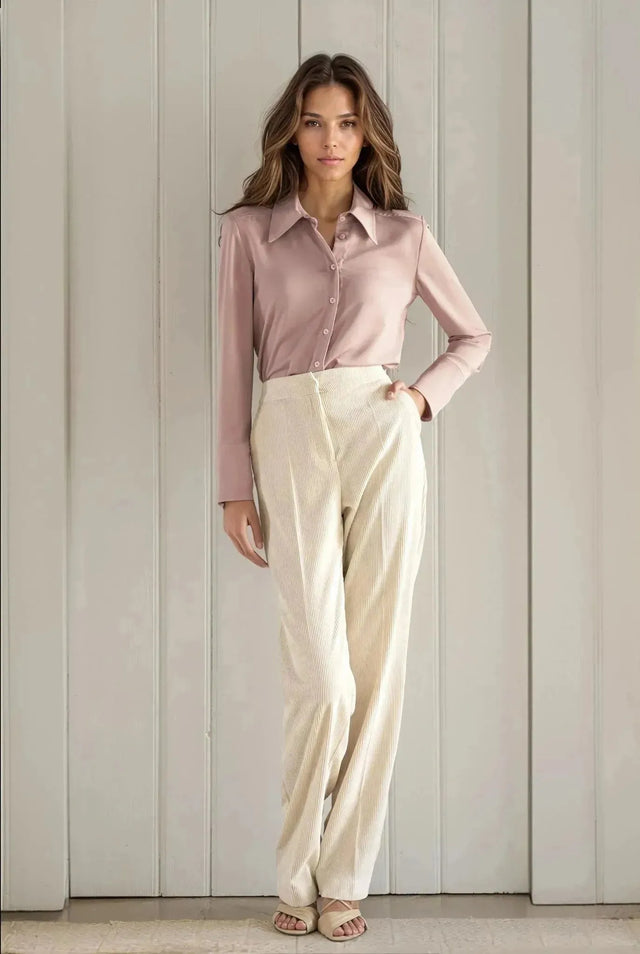 Femme portant un pantalon large en velours côtelé beige et une chemise rose