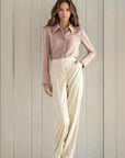 Femme portant un pantalon large en velours côtelé beige et une chemise rose