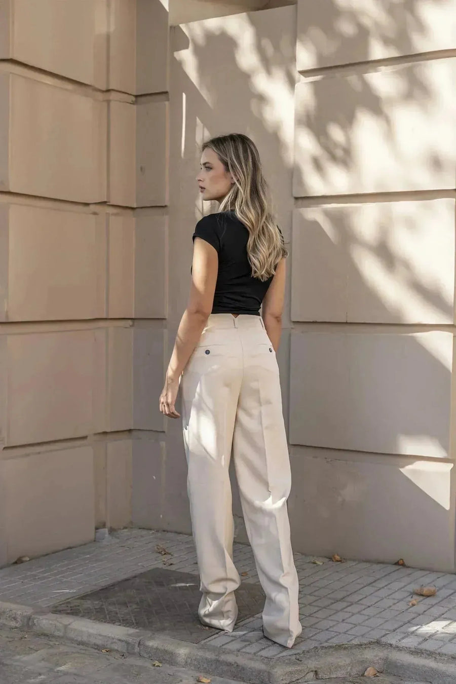 Femme portant un look homme avec t-shirt noir et pantalon plissé look homme