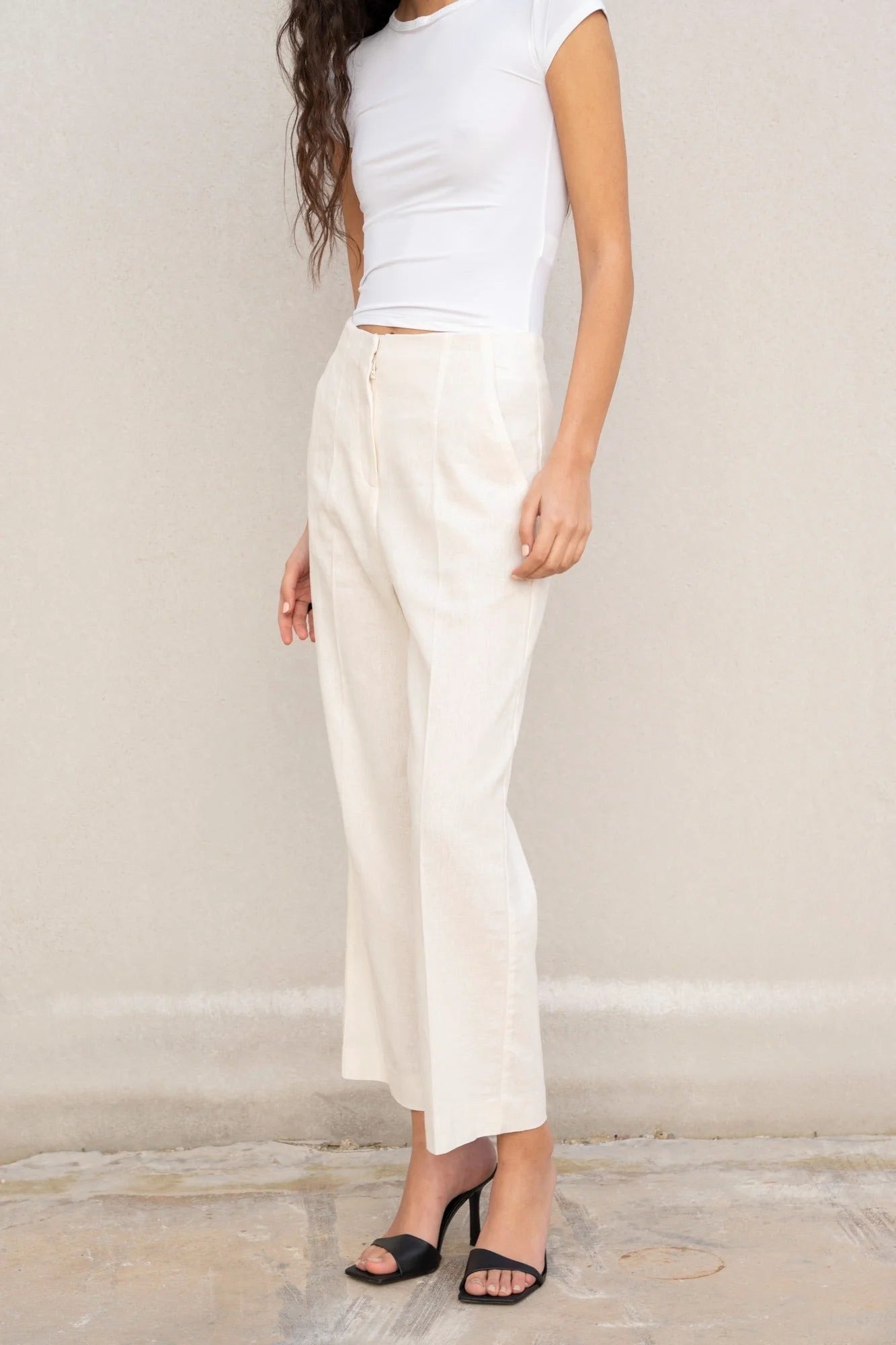 Femme portant un pantalon en lin blanc taille haute et top blanc, style lin chic