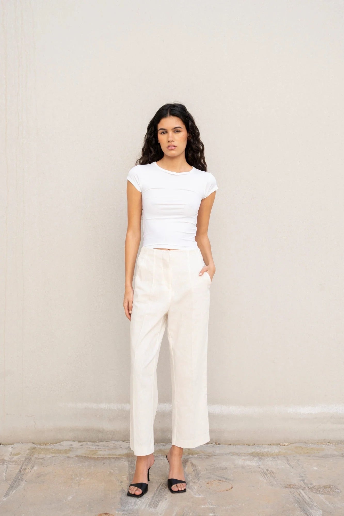 Femme portant un pantalon en lin blanc taille haute, style chic, avec crop top blanc