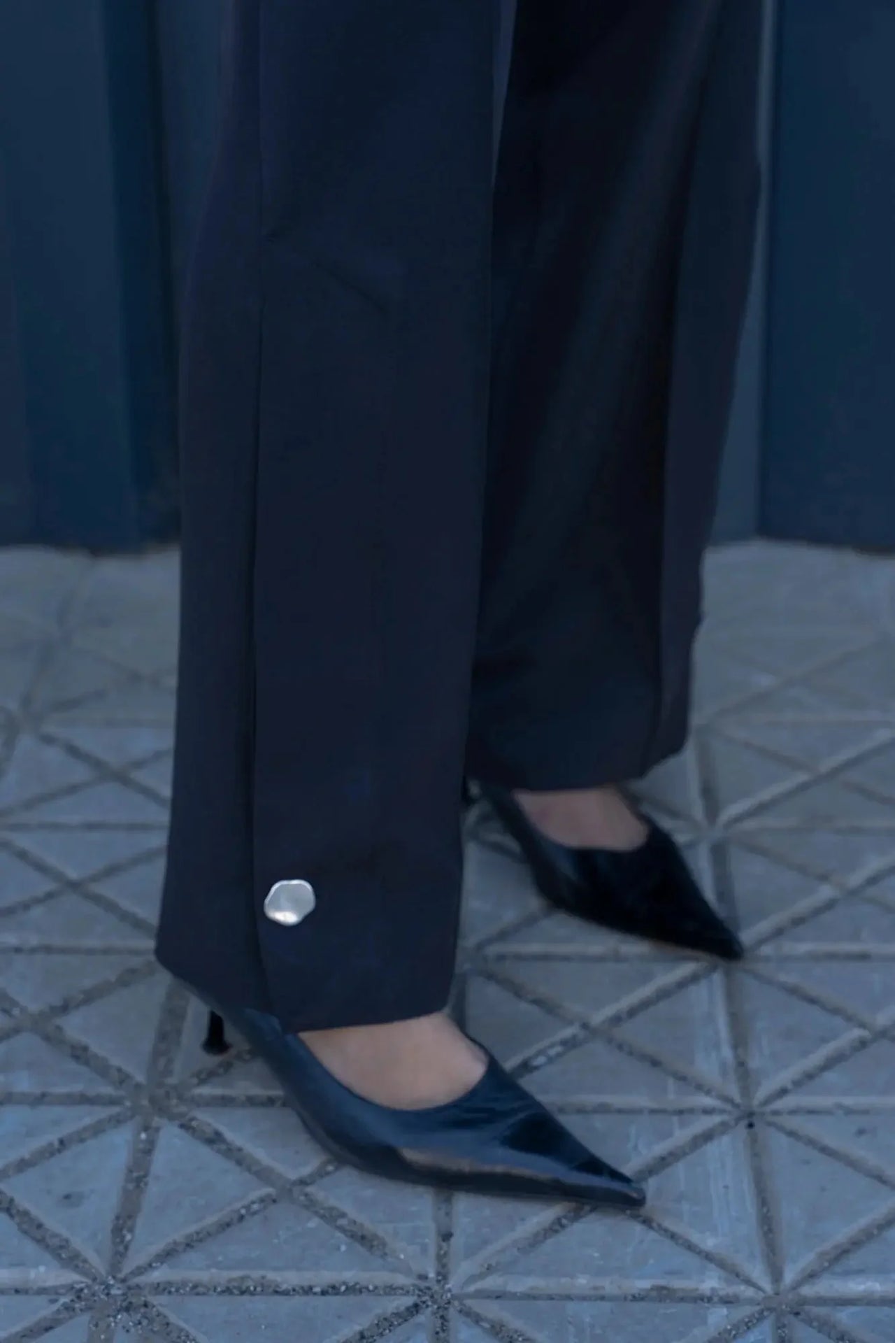Détail des boutons argentés du Pantalon Élégant Femme, accompagné de chaussures noires, illustrant le soin apporté à la mode.