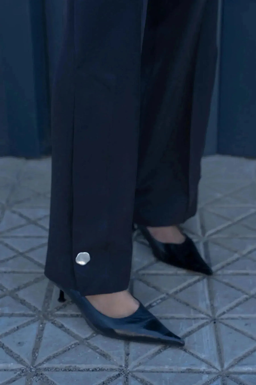 Détail des boutons argentés du Pantalon Élégant Femme, accompagné de chaussures noires, illustrant le soin apporté à la mode.