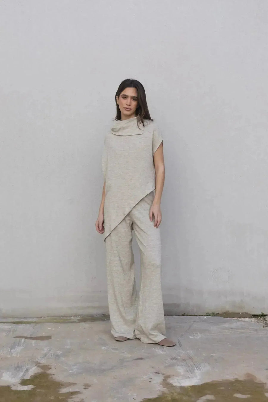 Femme posant avec assurance dans une tenue complète en haut asymétrique et pantalon tricot femme à jambes larges, illustrant une élégance décontractée.