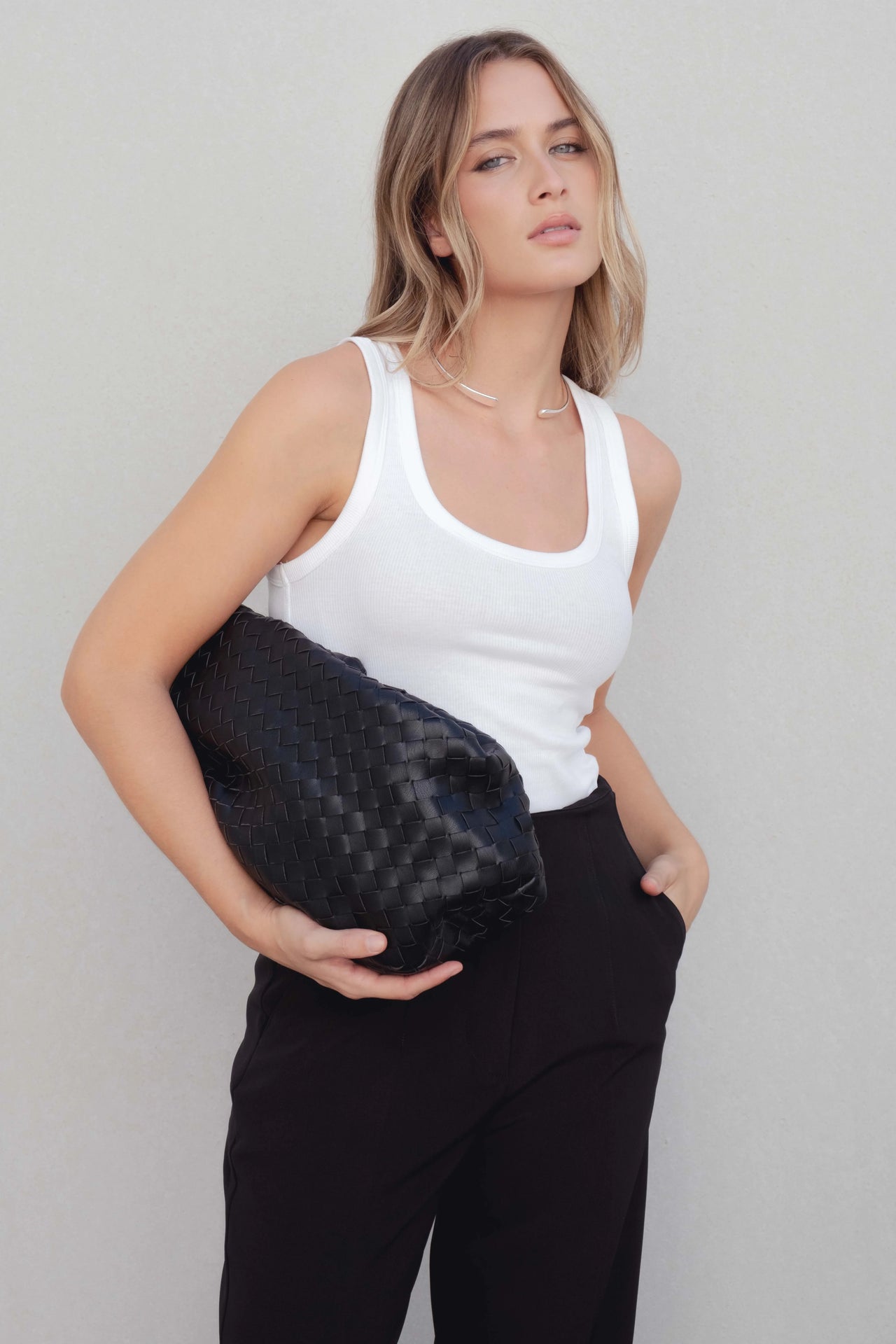 Femme portant un pantalon à pince femme noir avec un haut blanc, affichant un look élégant et décontracté, idéal pour toutes les occasions.