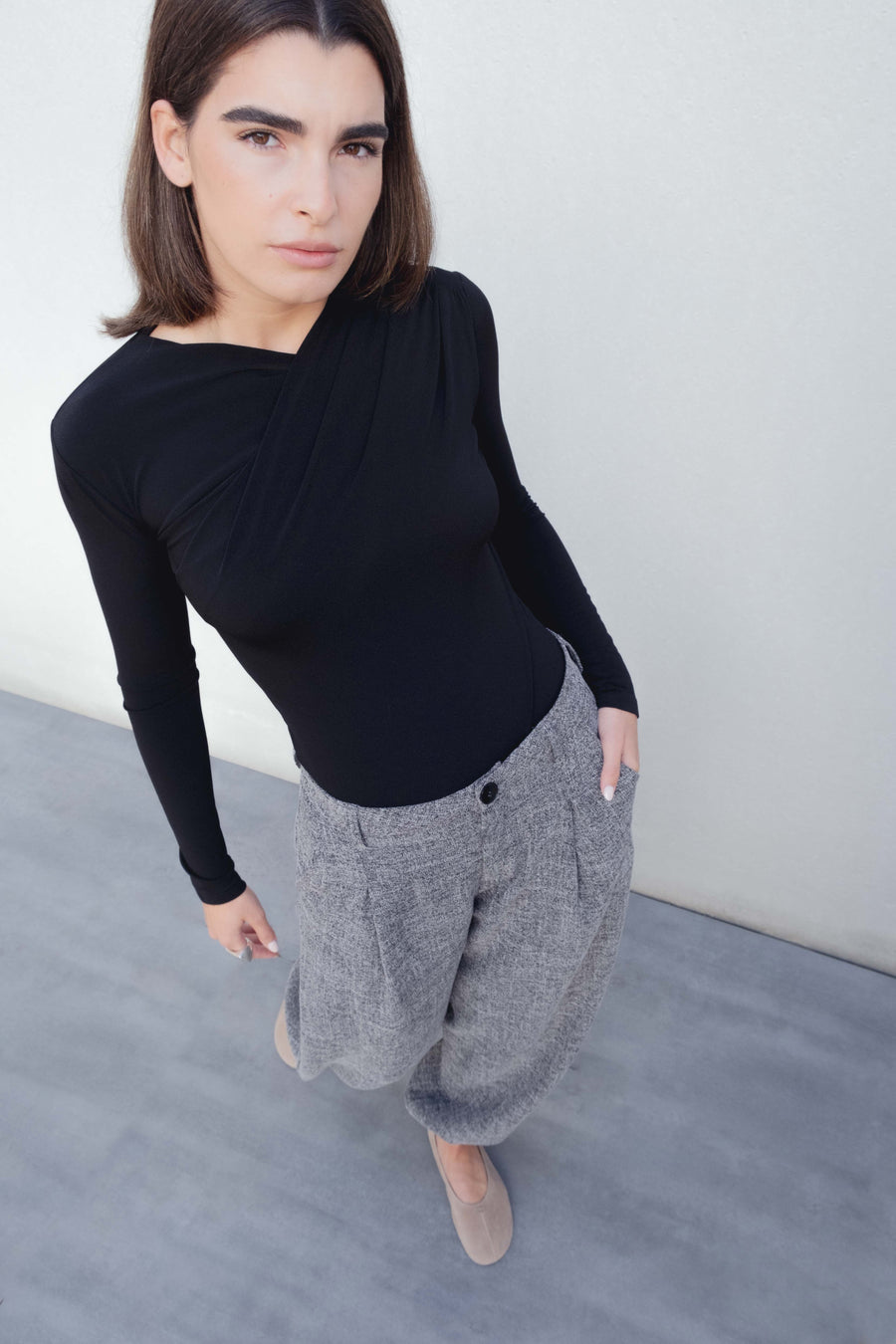 Modèle portant un pantalon ample structuré gris en polyester et viscose, idéal pour un look moderne et confortable.