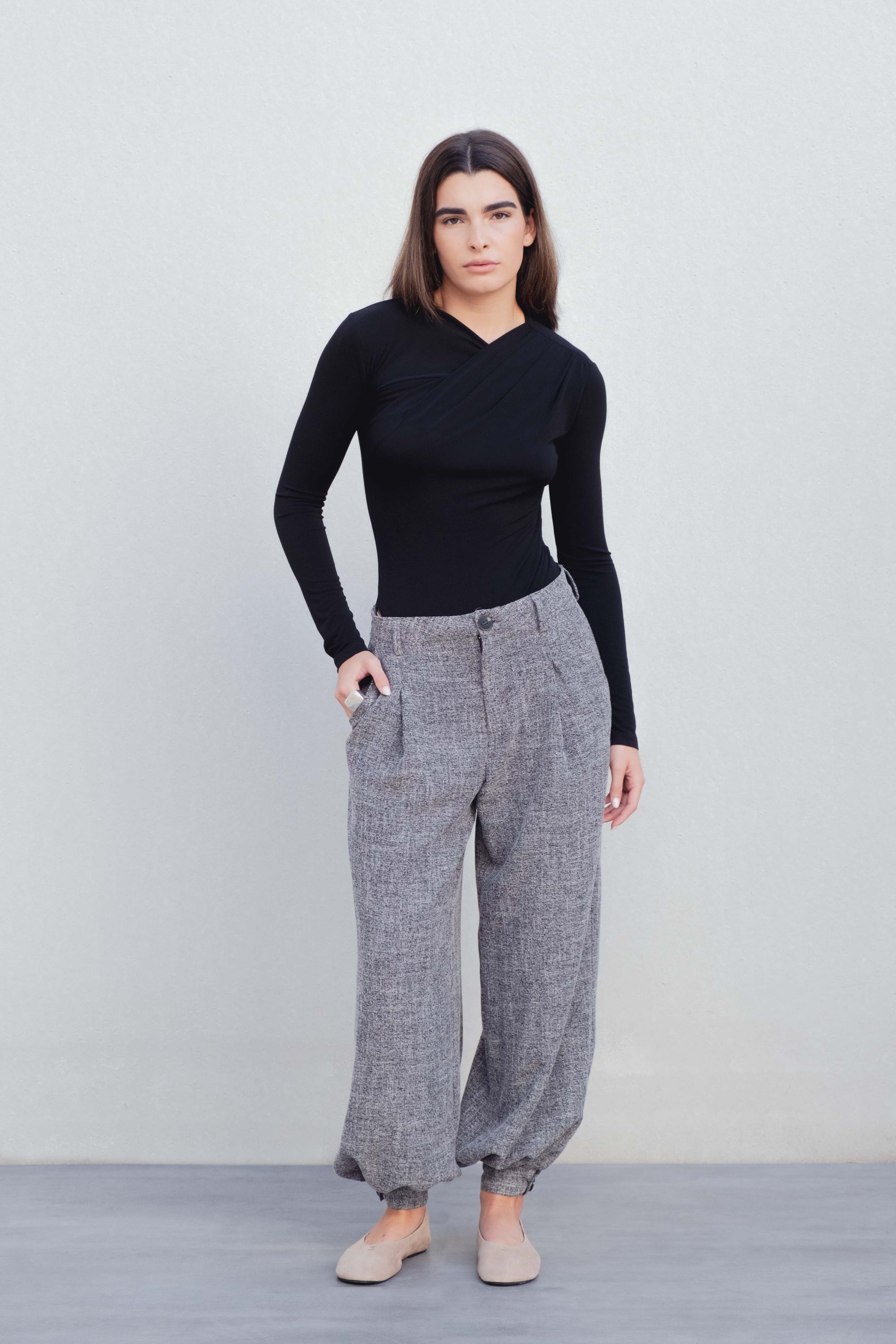 Femme debout dans un pantalon ample structuré gris, mettant en avant le style et le confort au quotidien, parfait pour la garde-robe.