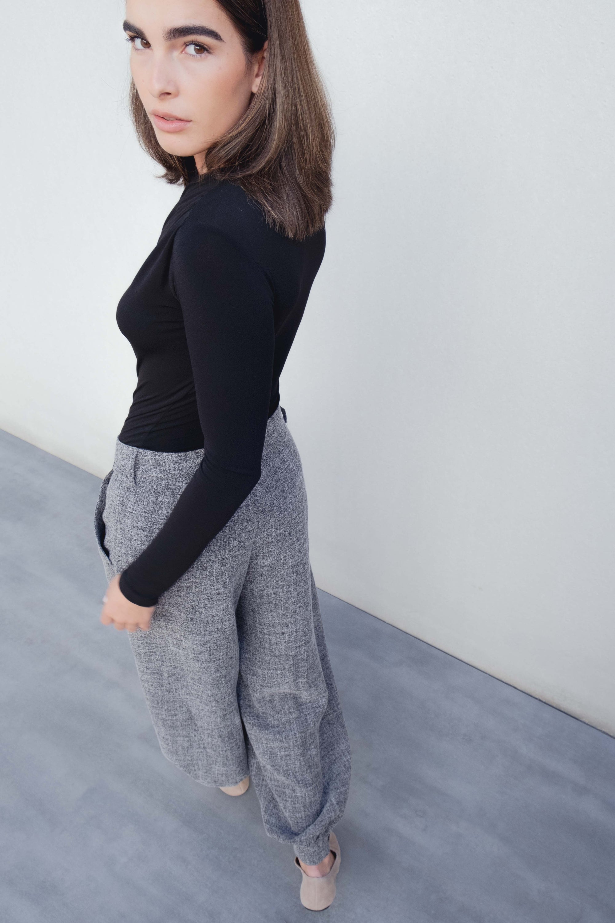 Vue de profil d'un pantalon ample structuré gris porté par un modèle, alliant élégance discrète et confort.