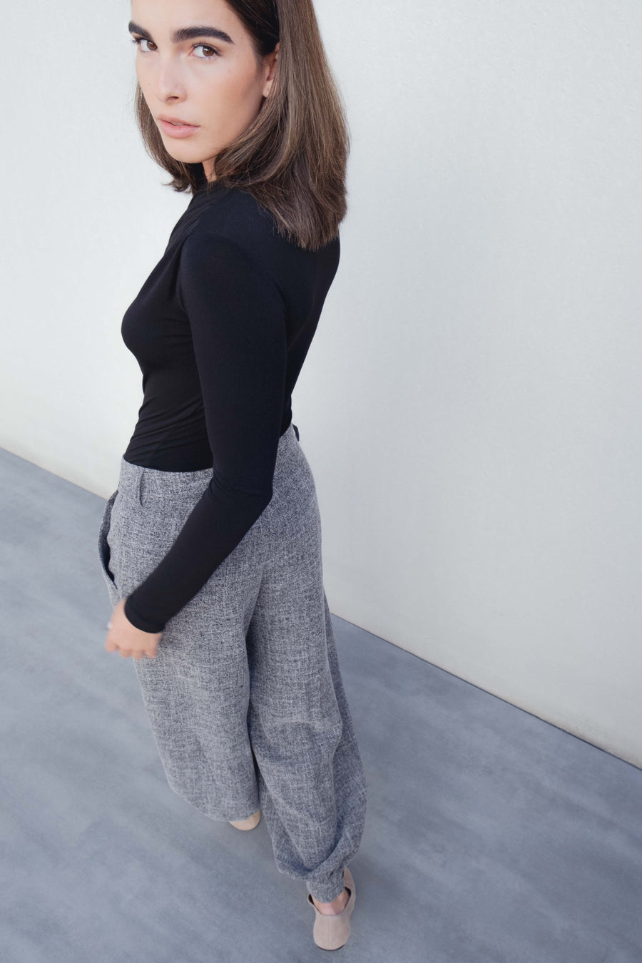 Vue de profil d'un pantalon ample structuré gris porté par un modèle, alliant élégance discrète et confort.