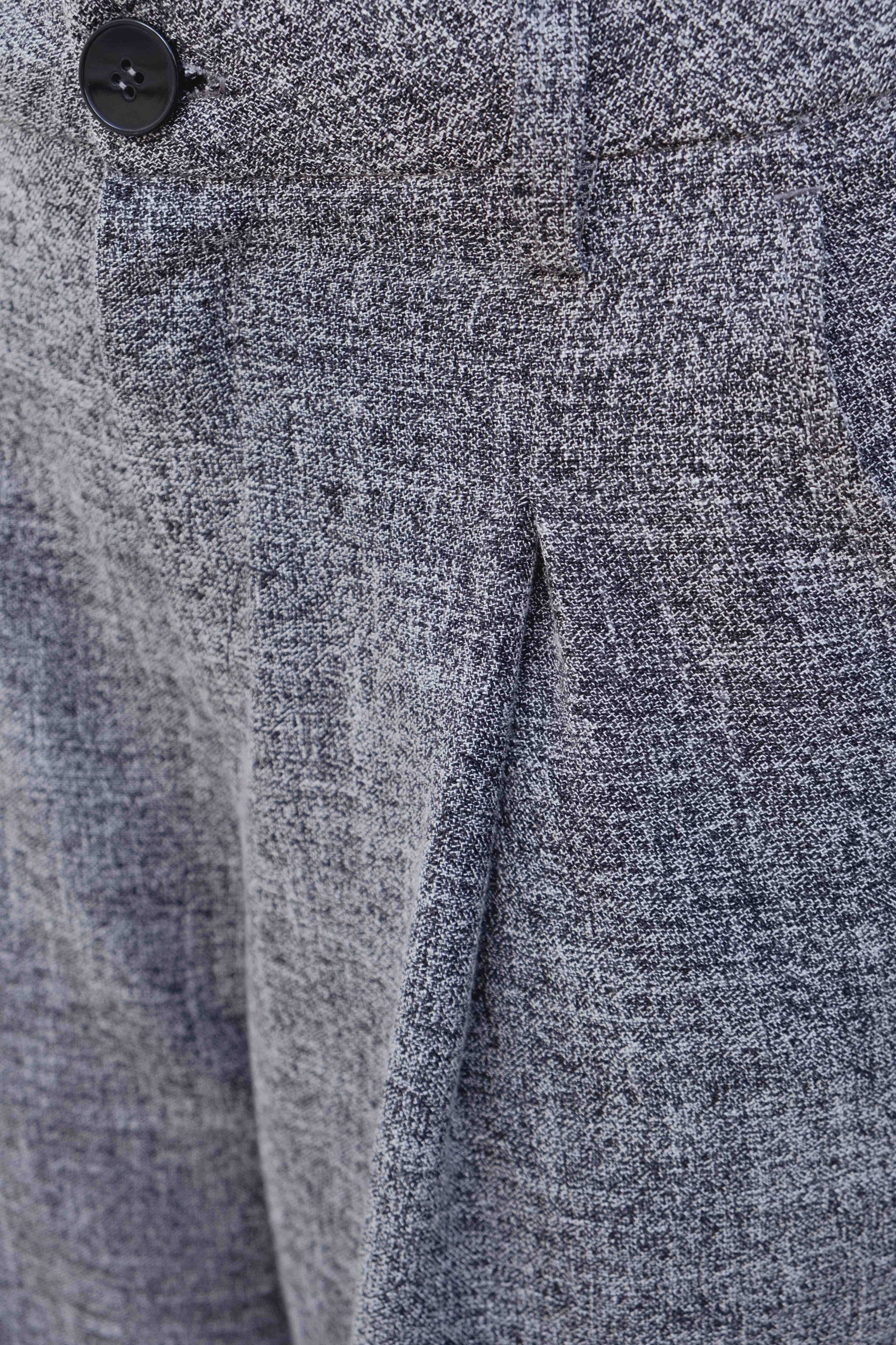 Détail du tissu d'un pantalon ample structuré gris, soulignant la qualité du matériau en polyester et viscose.
