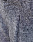 Détail du tissu d'un pantalon ample structuré gris, soulignant la qualité du matériau en polyester et viscose.