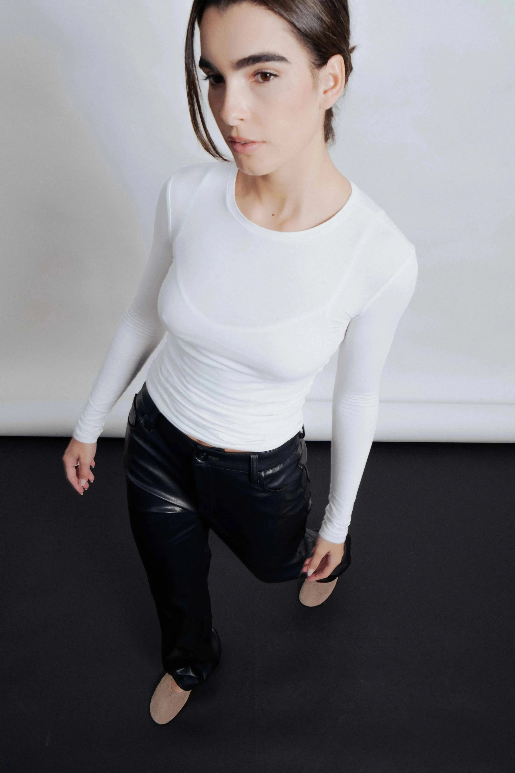 Femme portant un pantalon imitation cuir femme élégant, chic et polyvalent, associé à un haut blanc. Parfait pour toutes occasions.