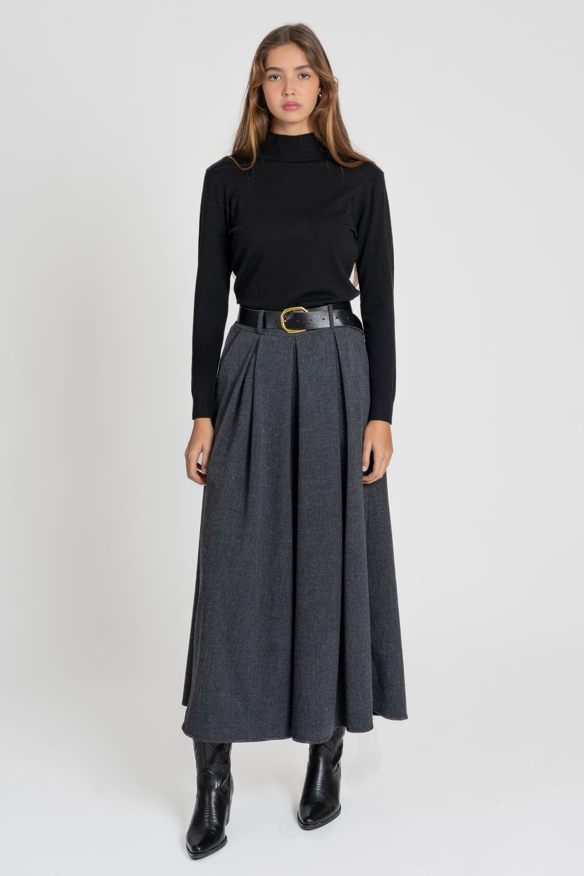 Femme dans une pose décontractée avec un pantalon large taille haute femme en gris.