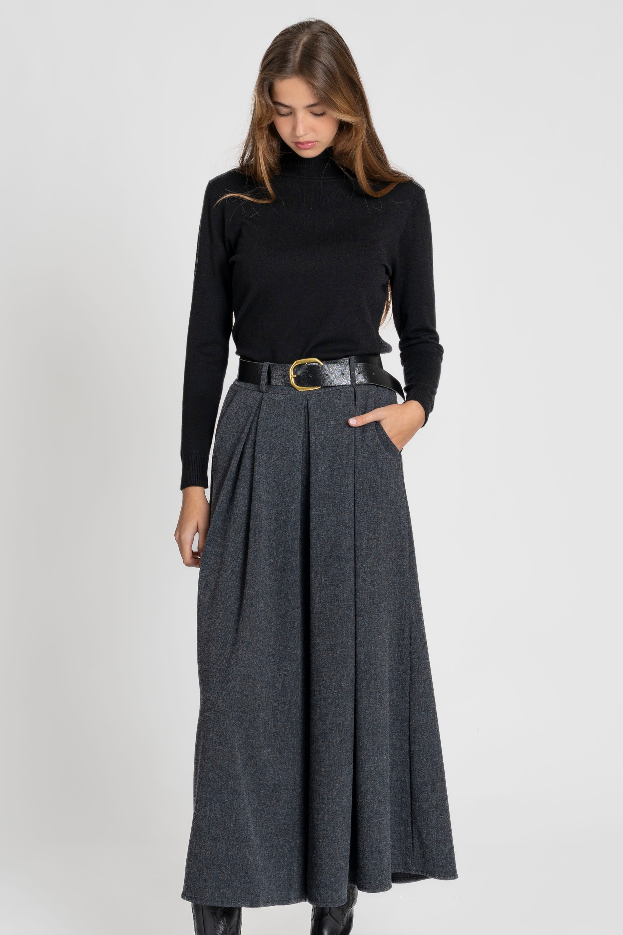 Femme en posture d'élégance avec un pantalon large taille haute femme en gris.