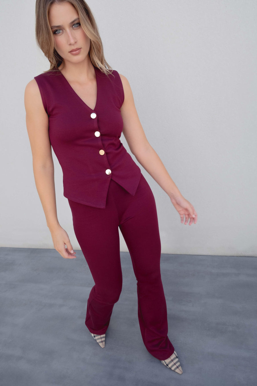 Pantalon en maille texturée taille haute flare bordeaux viscose, modèle femme stylé portant une blouse bordeaux et des escarpins, mettant en avant le pantalon maille femme.