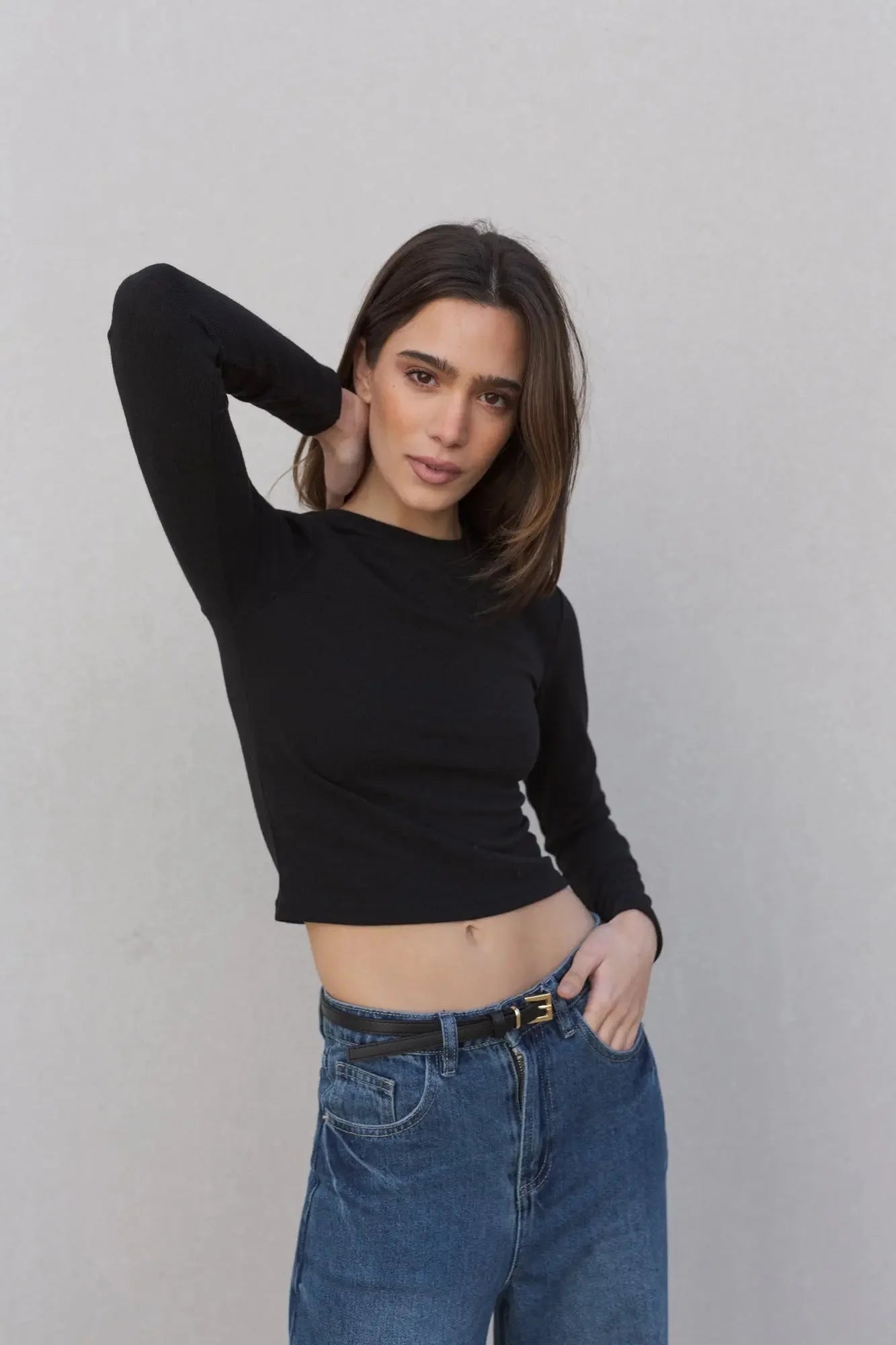Femme portant un pull basique col rond à manches longues en noir et jeans bleus