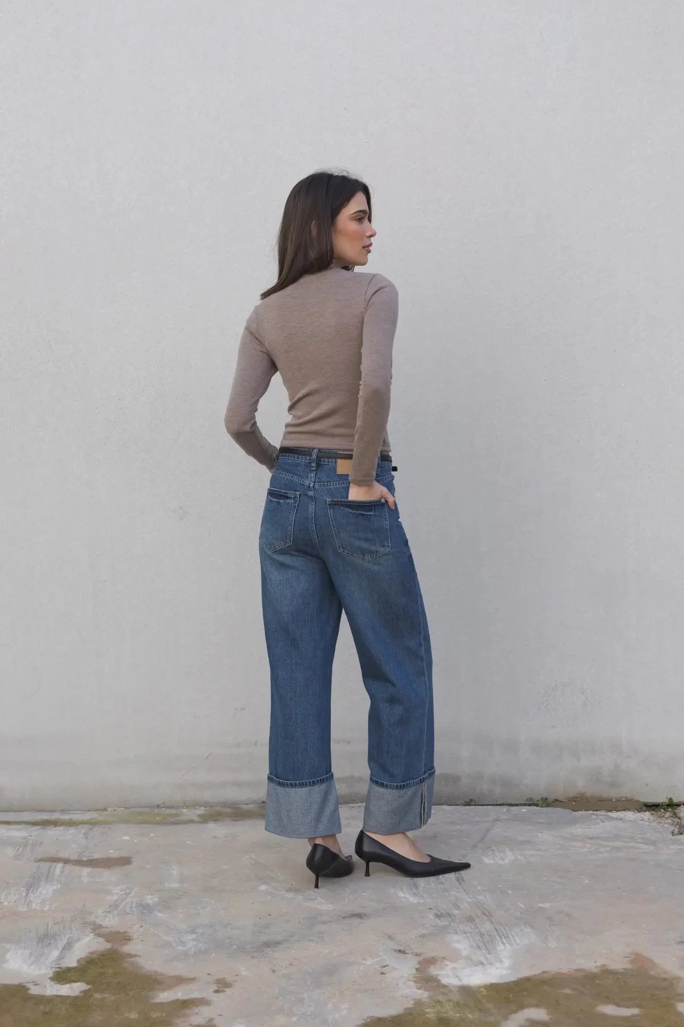 Femme portant un pull basique col rond à manches longues, jeans bleus et talons noirs
