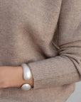 Détail du pull laine femme col rond marron avec un bracelet argenté, combinaison de style.