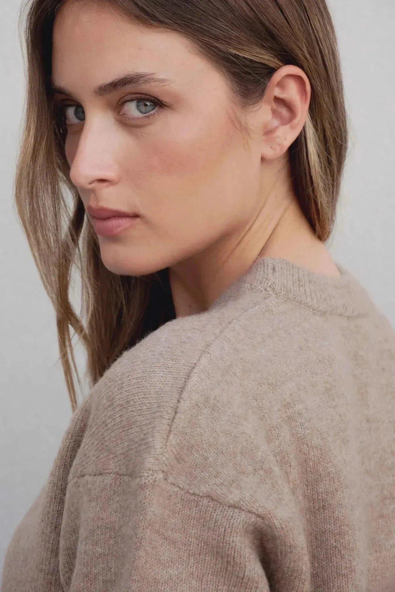 Profil d'une femme portant un pull laine femme col rond marron, style élégant et décontracté.