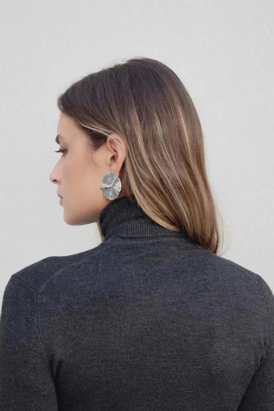 Vue arrière d'une femme avec pull col roulé femme gris foncé, mettant en valeur le col et les accessoires.