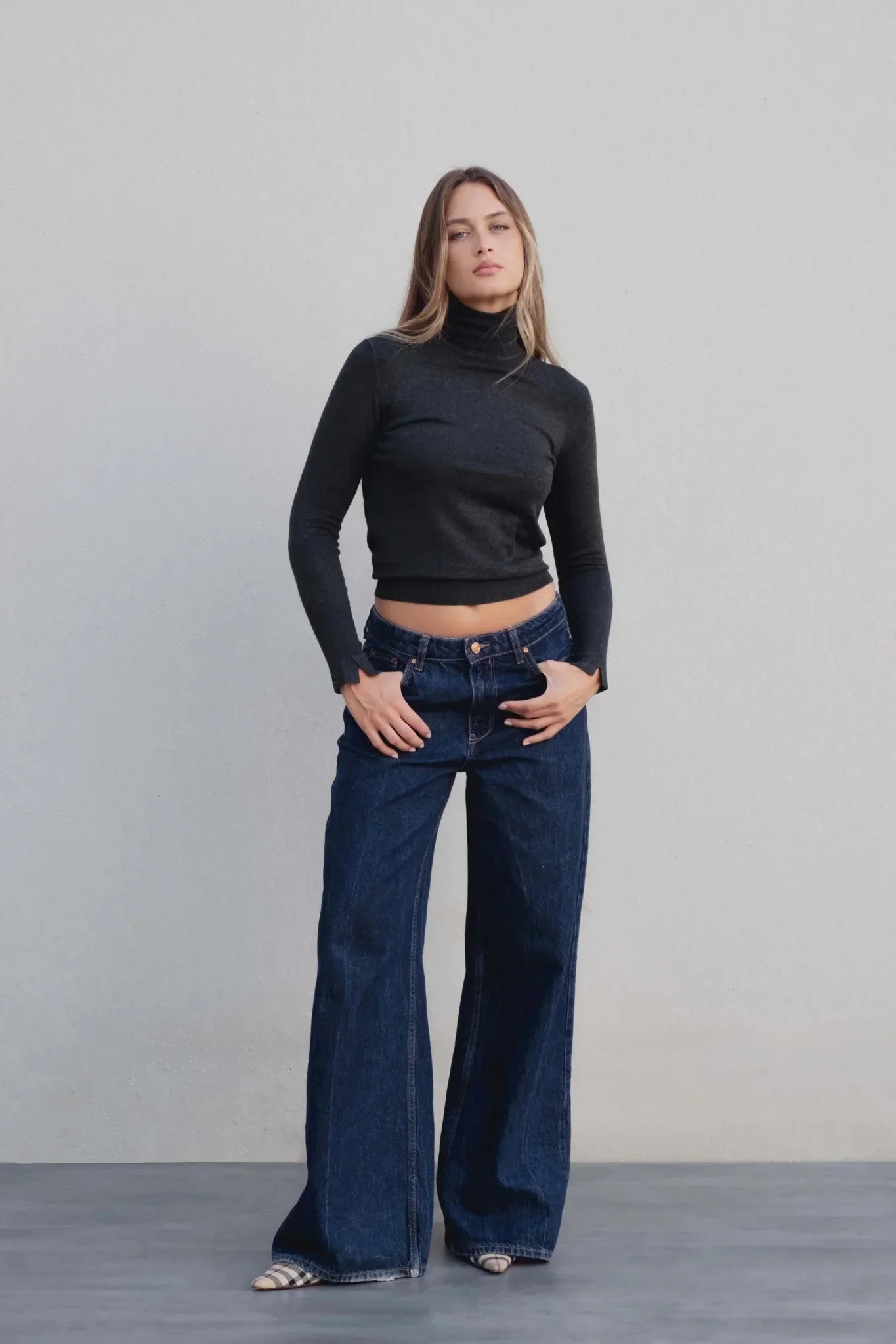 Femme portant un pull col roulé gris foncé et jeans large-leg, style basique élégante