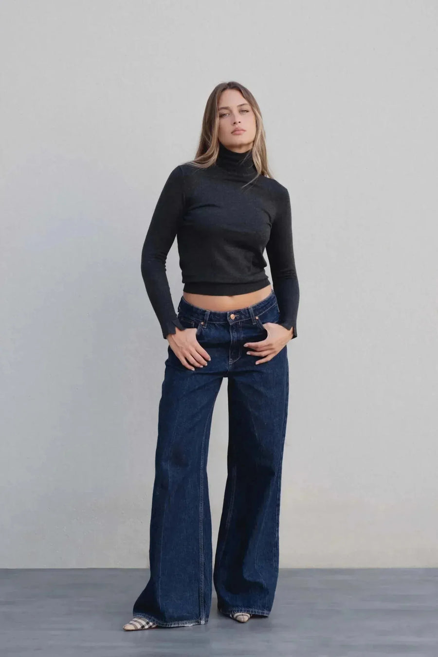Femme affichant un style décontracté avec un pull col roulé femme gris foncé, associé à un jean large.