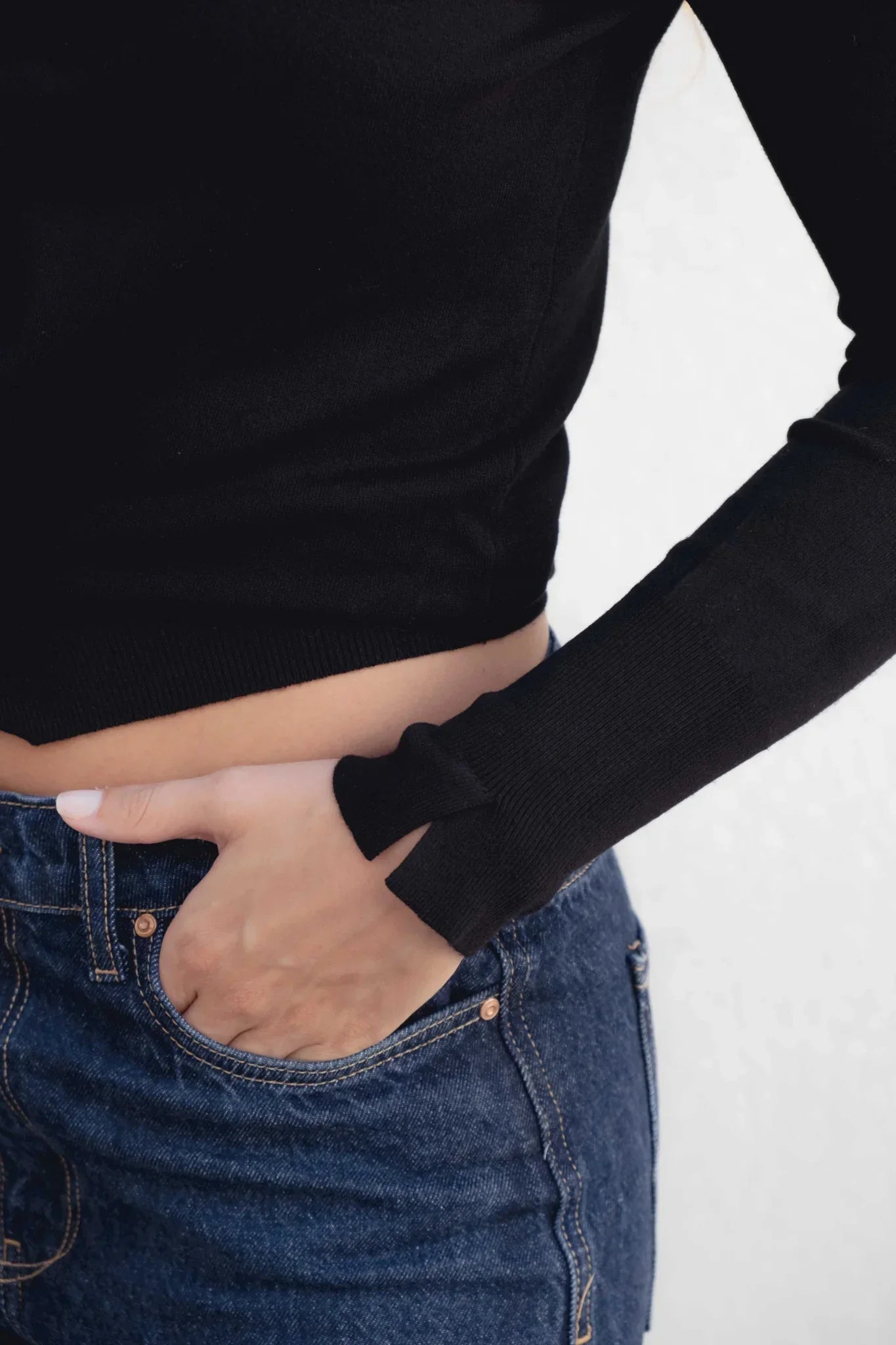 Person portant un pull col roulé noir en maille fine avec jean bleu foncé
