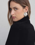 Femme avec un pull col roulé noir en maille fine, accessoirisée avec de grandes boucles d'oreilles, pour un look élégant.