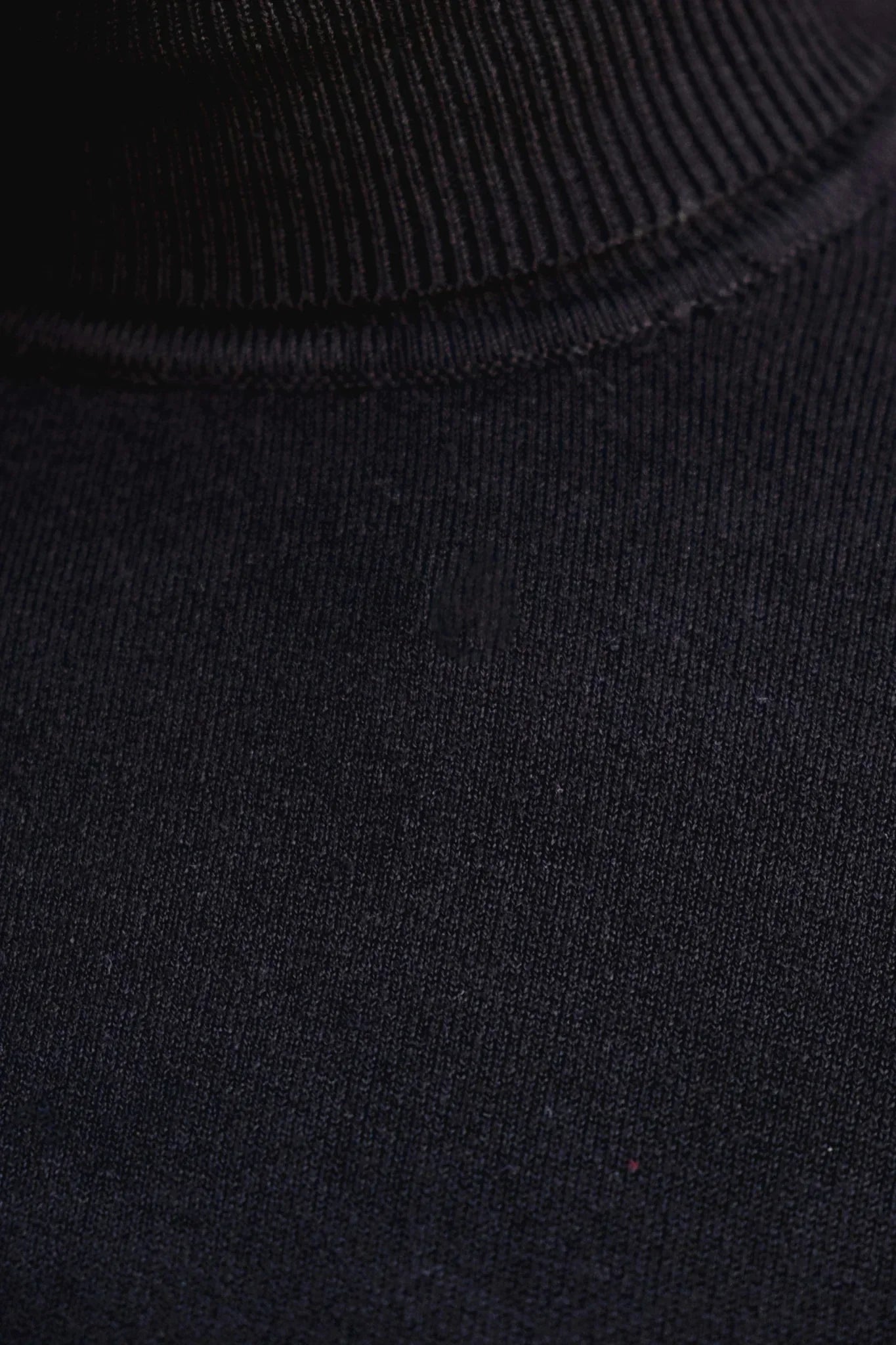Close-up du pull col roulé noir en maille fine, élégance et confort assurés