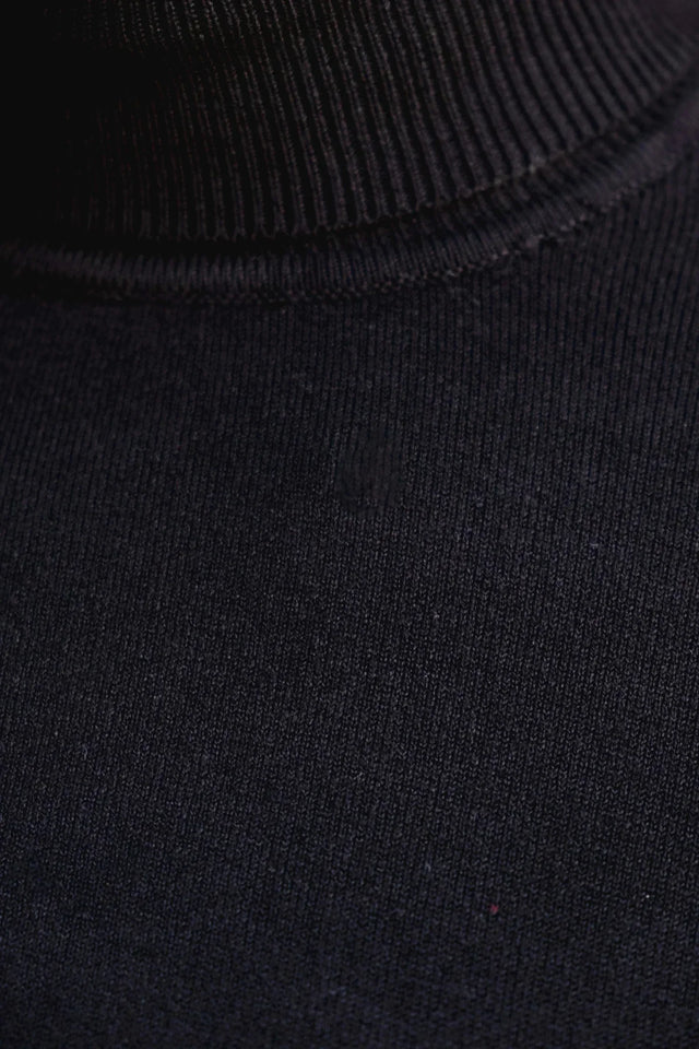 Zoom sur le col du pull col roulé noir femme, mettant en avant la matière douce et extensible.