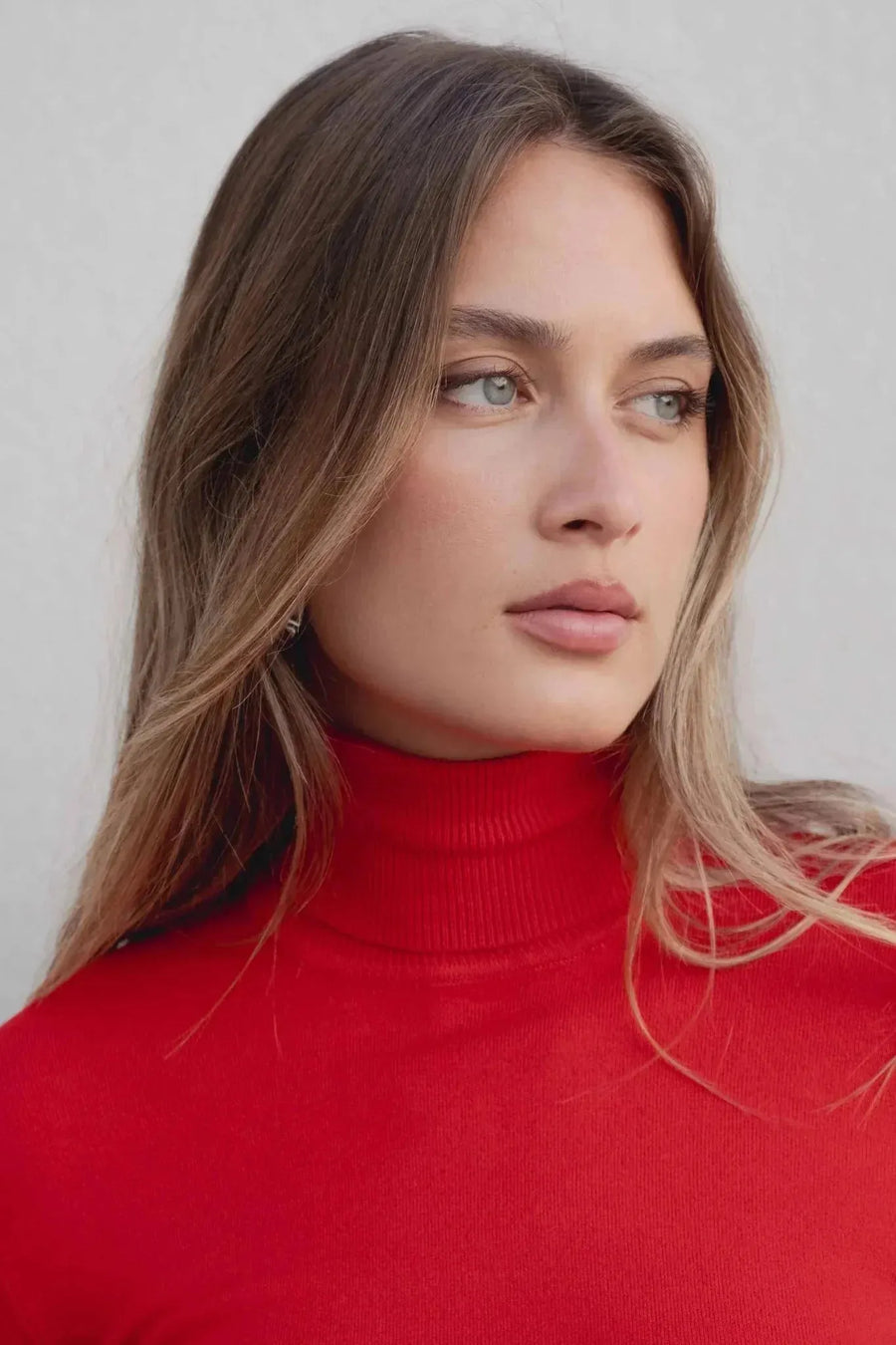 Détail sur le visage d'un modèle avec pull col roulé femme rouge, mettant en valeur le col roulé et un look chic.