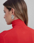 Vue arrière d'un modèle portant un pull col roulé femme rouge, soulignant le col stylé et les boucles d'oreilles modernes.