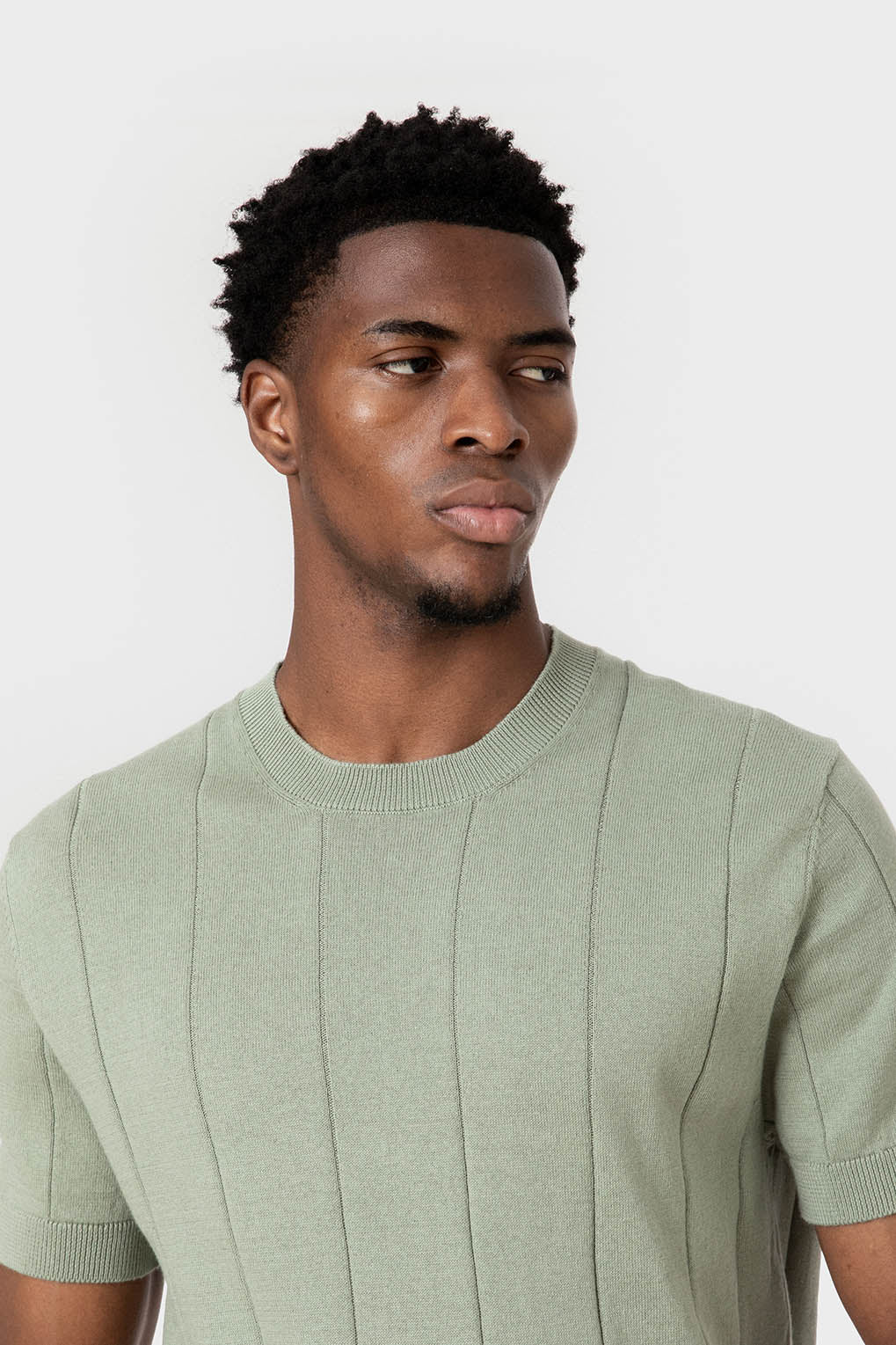 Gros plan sur le col rond et la maille du pull vert sauge