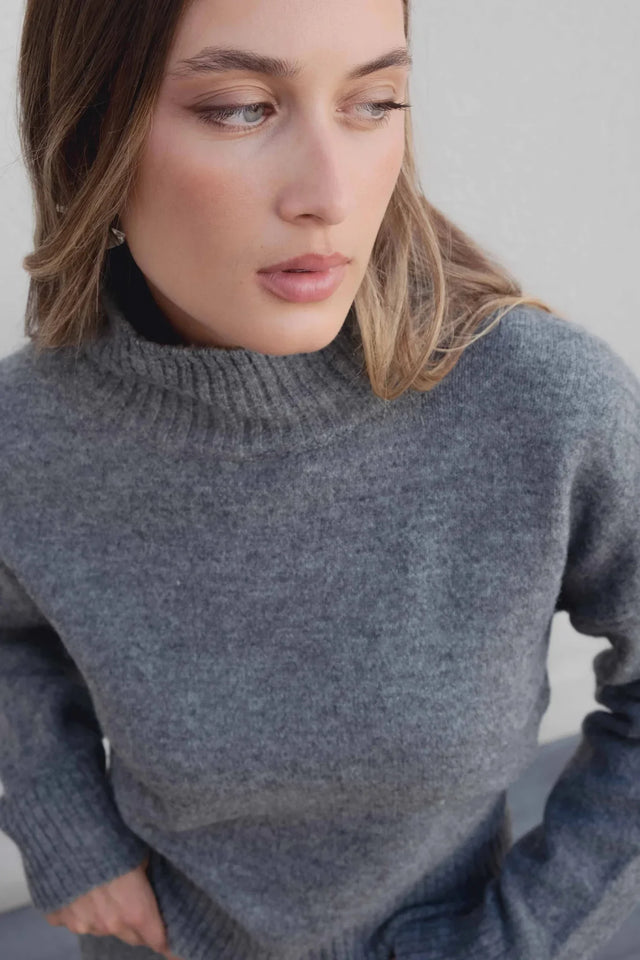 Modèle féminin portant le pull col roulé femme court gris, mettant en avant le col montant.