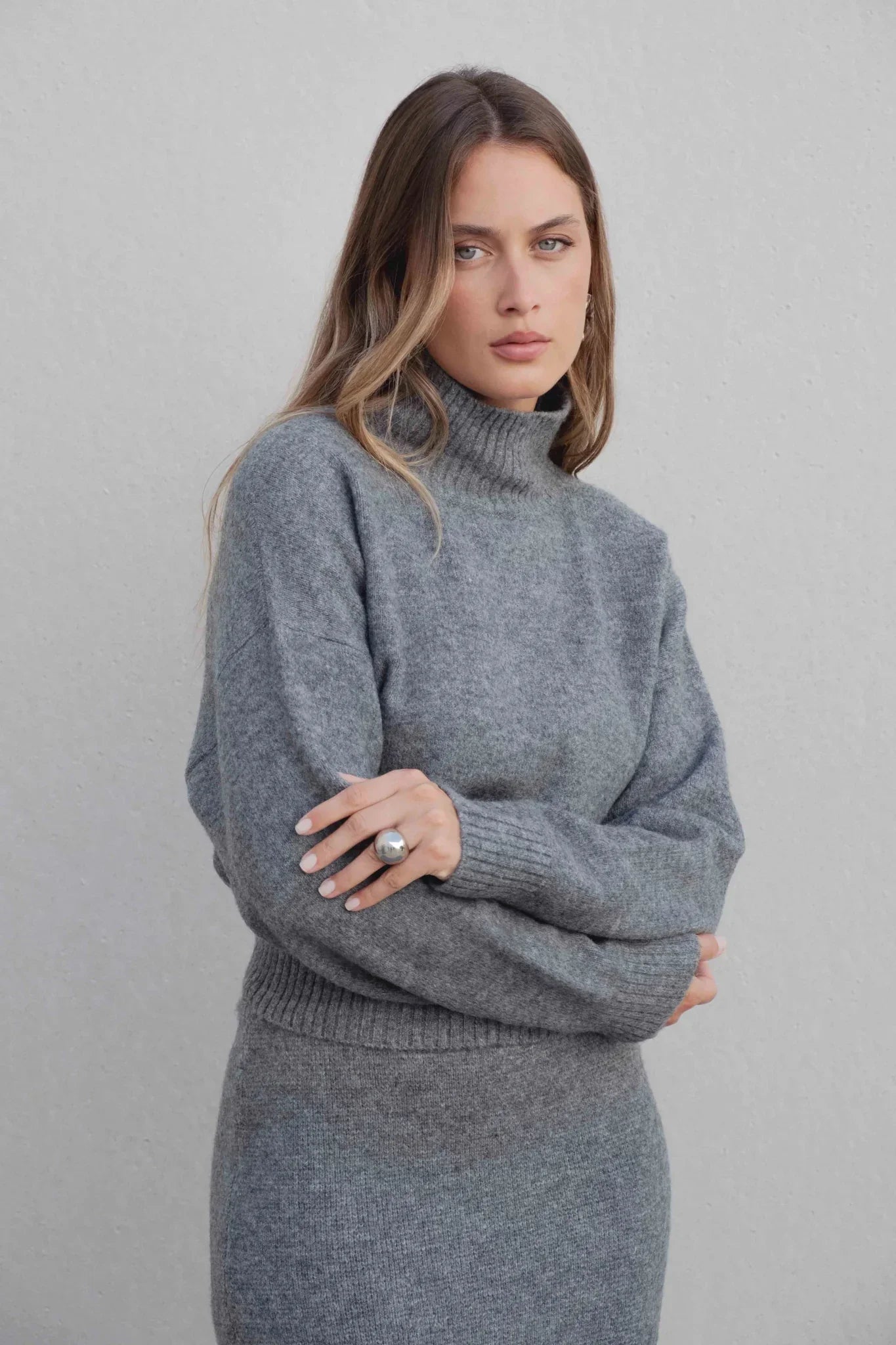 Femme portant un pull court gris à col montant et jupe assortie