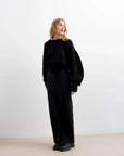 Pull Laine Femme Oversize à Manches Ballon - Femme en pull laine femme noir, se tenant debout, style élégant.