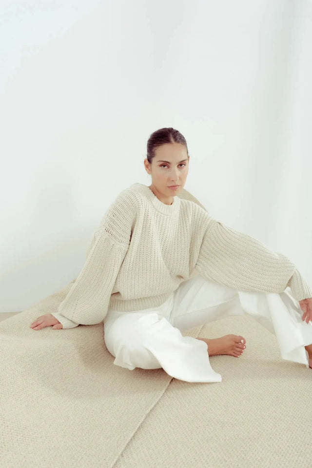 Pull Laine Femme Oversize à Manches Ballon - Femme souriante en pull laine femme beige assise confortablement.