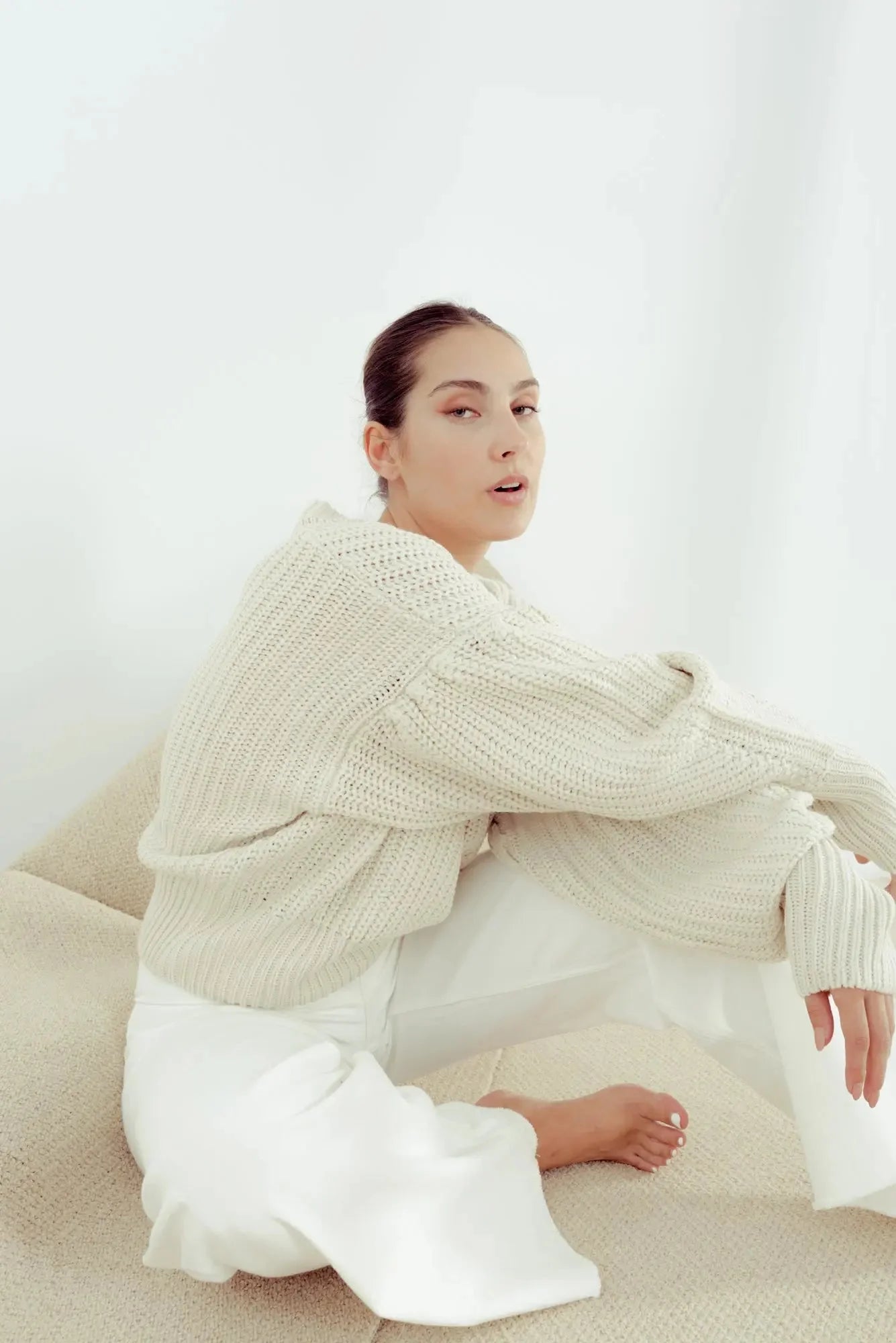 Femme portant un pull crème en tricot surdimensionné à manches ballon et jupe satinée