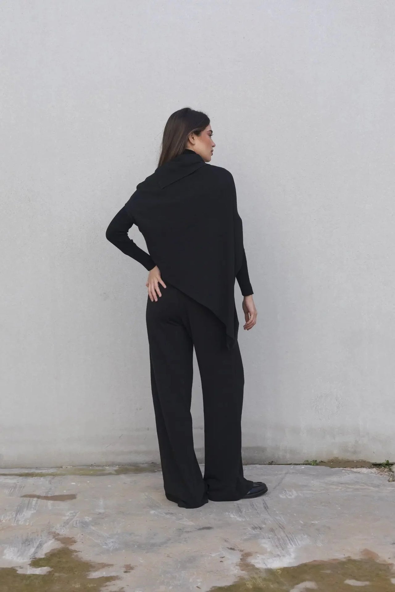 Vue arrière d'une femme vêtue d'un pull long femme noir à col bénitier, alliant style et confort.