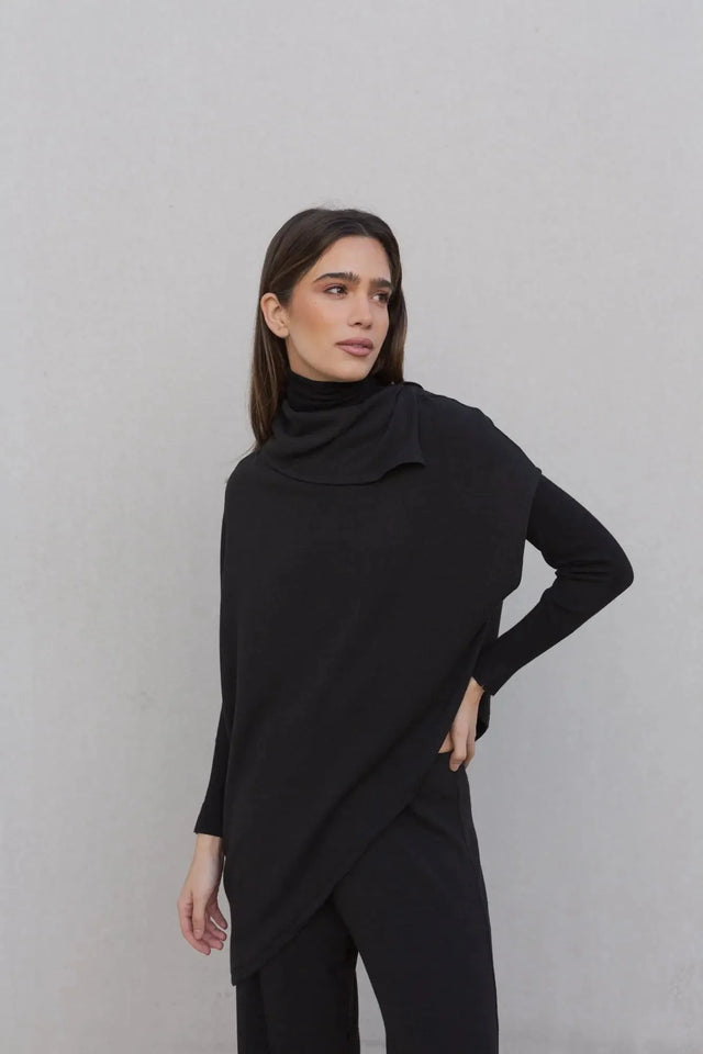 Femme portant un pull long femme noir à col bénitier, combinant élégance et chaleur.
