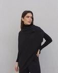 Femme portant un pull long femme noir à col bénitier, combinant élégance et chaleur.