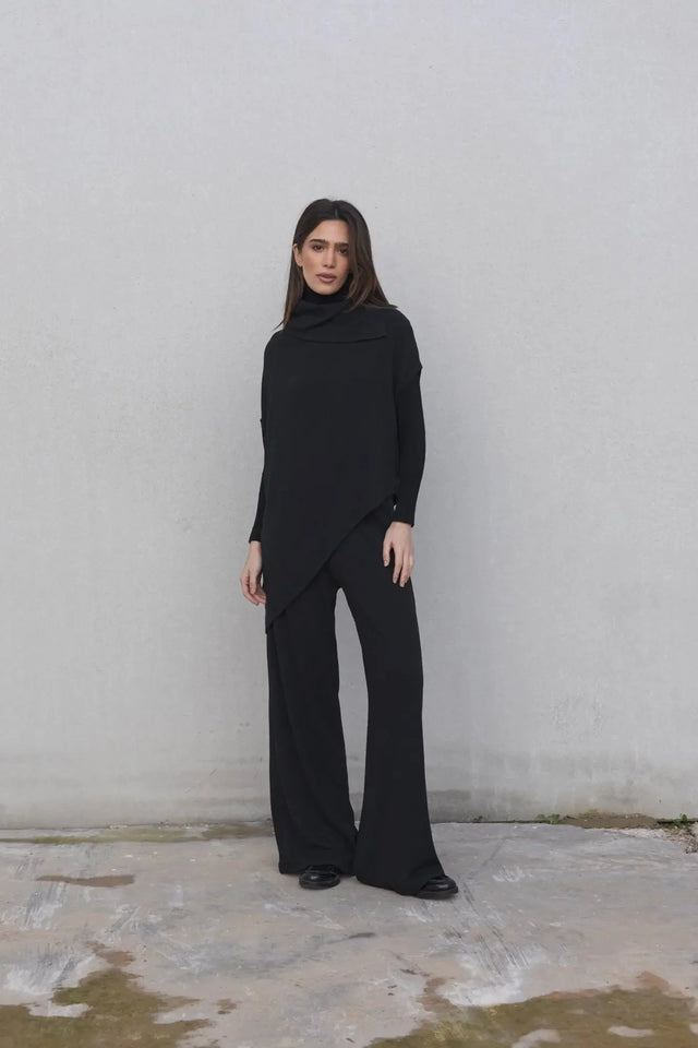 Modèle féminin en pull long femme noir à col bénitier, parfait pour un look chic et décontracté.