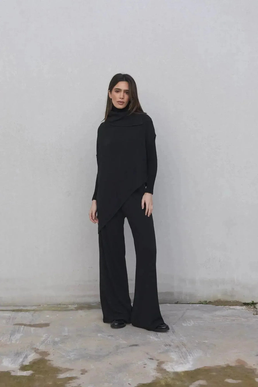 Modèle féminin en pull long femme noir à col bénitier, parfait pour un look chic et décontracté.