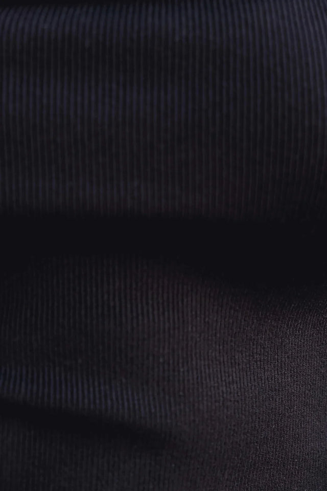 Zoom sur la texture du pull femme maille noir à épaules dénudées, mettant en avant la maille douce et légère.